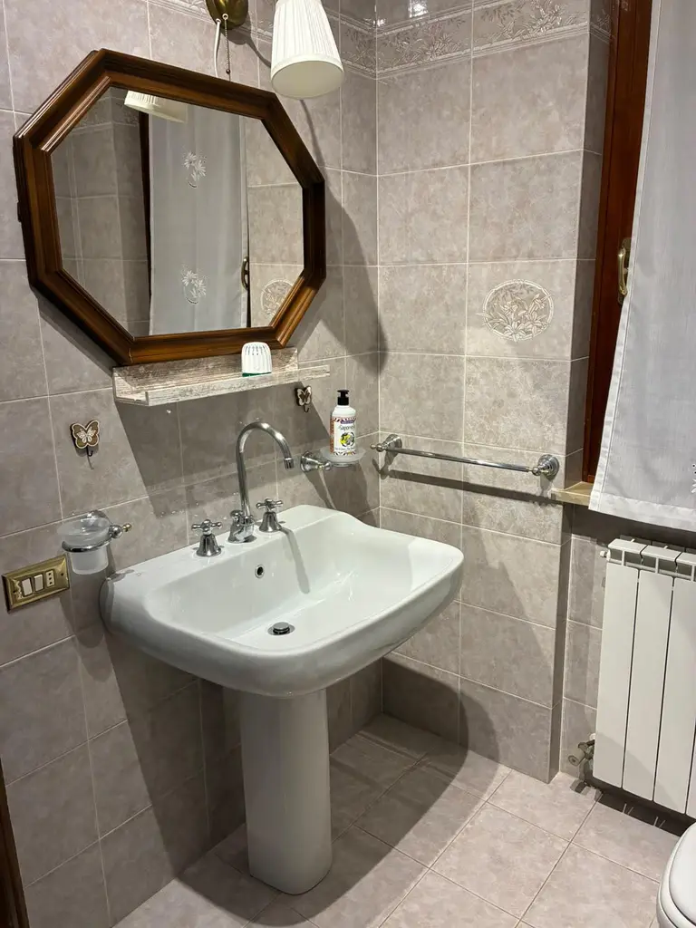 Il lavabo del bagno principale con lo specchio ottagonale in legno