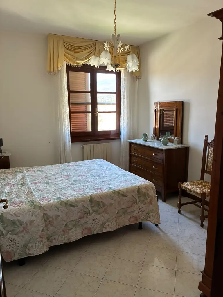 La camera padronale con il letto, il comò con lo specchio e la finestra sulle colline