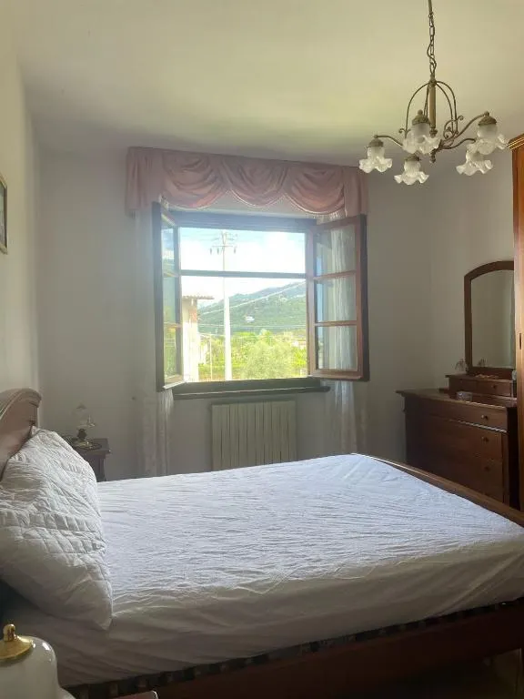 La camera matrimoniale con il letto in legno e la finestra aperta sulle colline