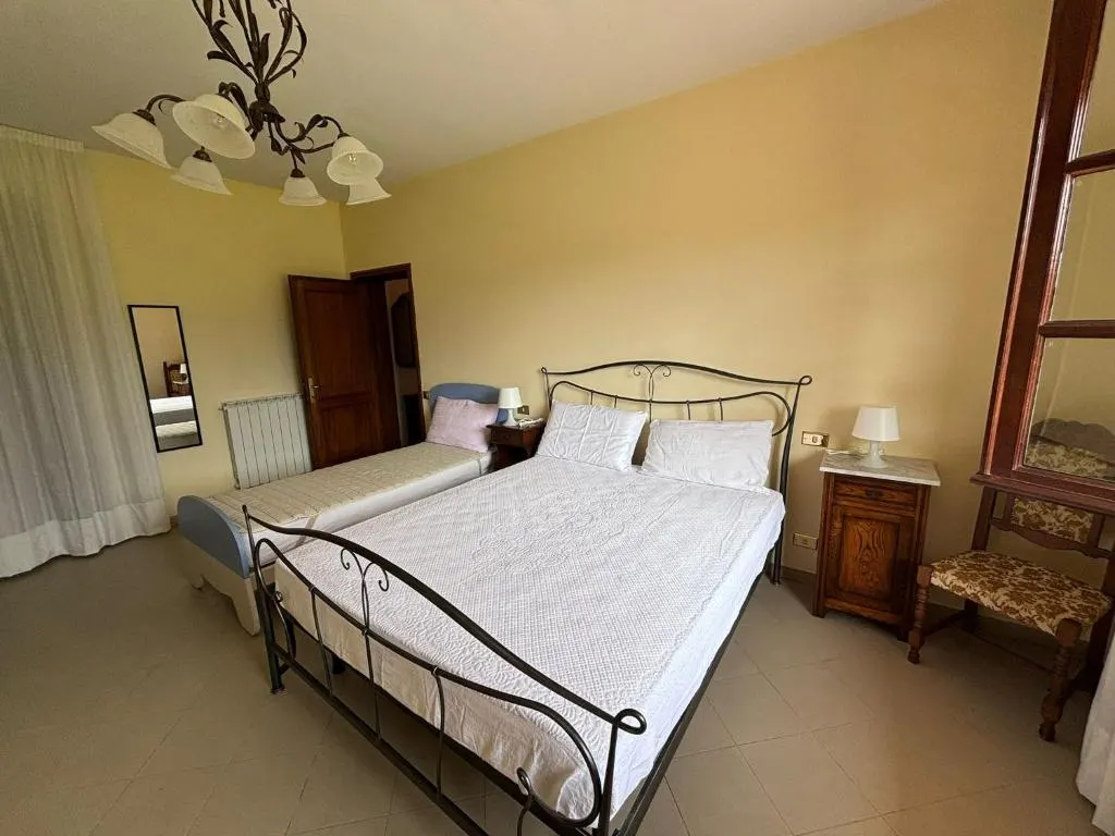 La camera tripla con il letto matrimoniale in ferro battuto, il letto singolo e i comodini