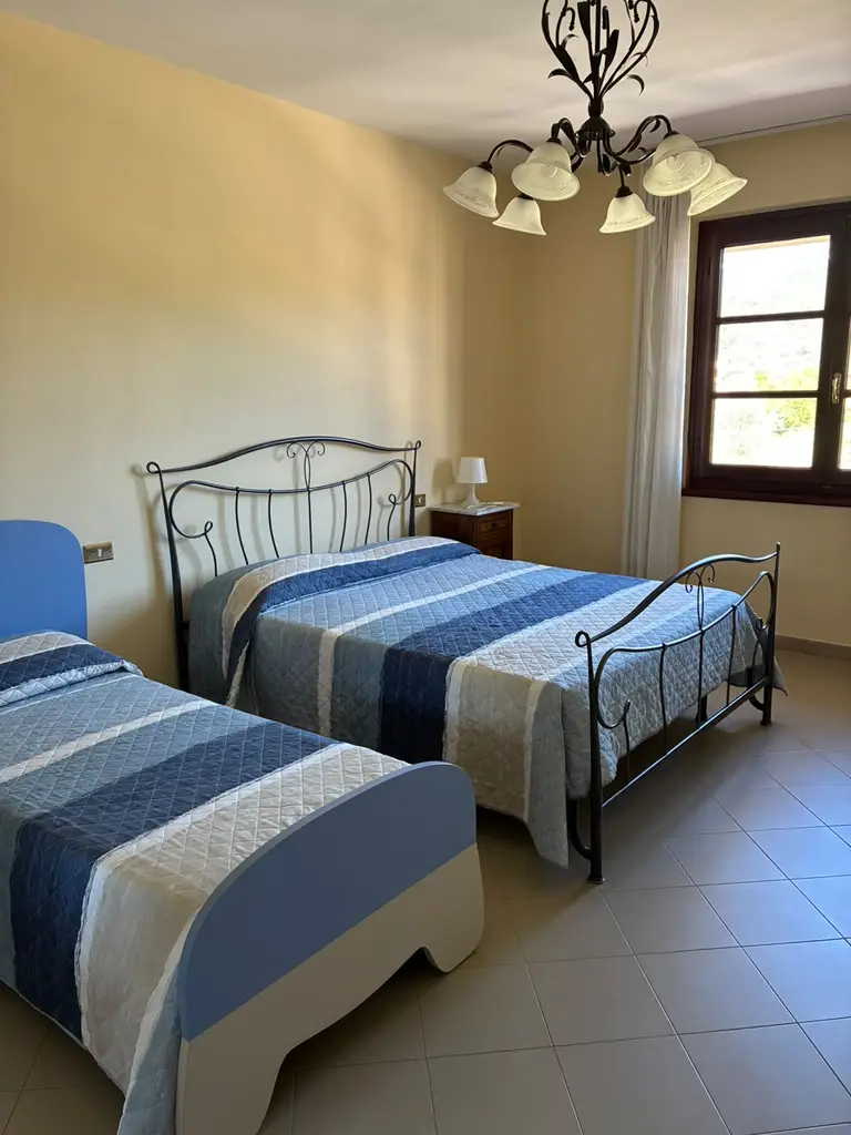 La camera tripla con il letto matrimoniale in ferro battuto, il letto singolo e la finestra