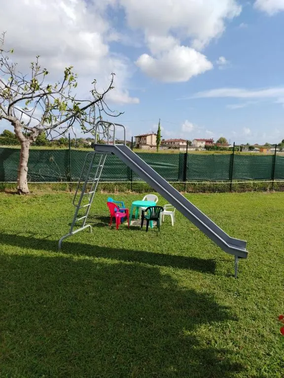 Lo scivolo per i bambini sul prato del giardino, con il tavolino e le sedie colorate