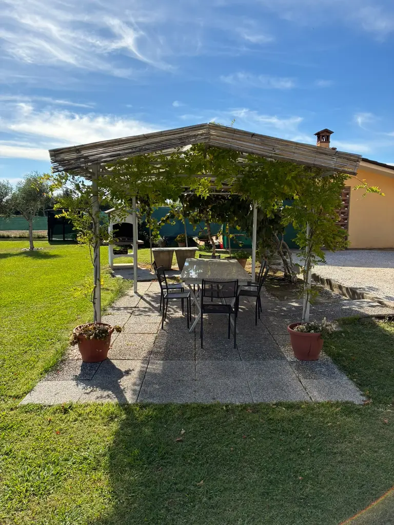 Il tavolo apparecchiabile sotto il pergolato, con le sedie e i vasi di fiori