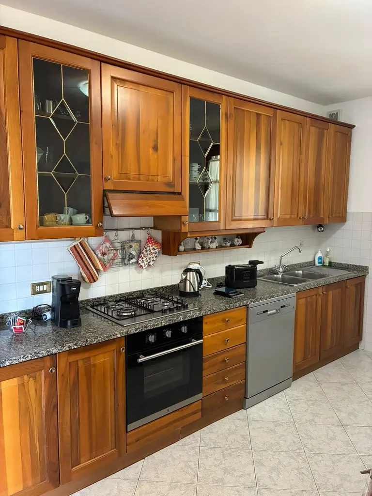 La cucina in legno con piano cottura, forno, lavastoviglie, bollitore, tostapane e macchina del caffè