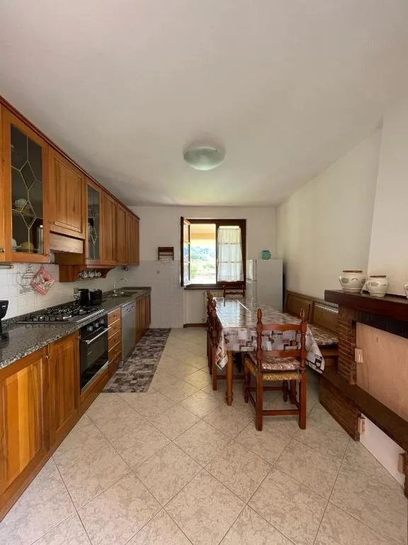 La cucina attrezzata con piano cottura, forno e il tavolo davanti alla finestra