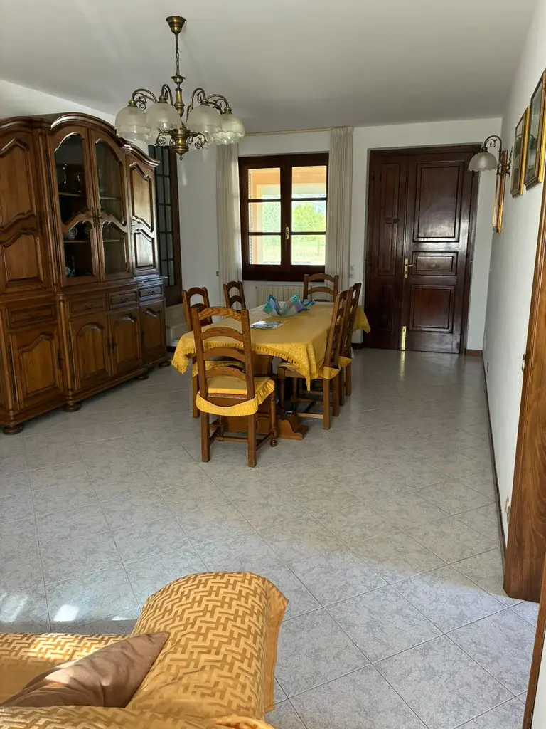 La sala vista dal divano: il tavolo, la credenza, la finestra e la porta d'ingresso