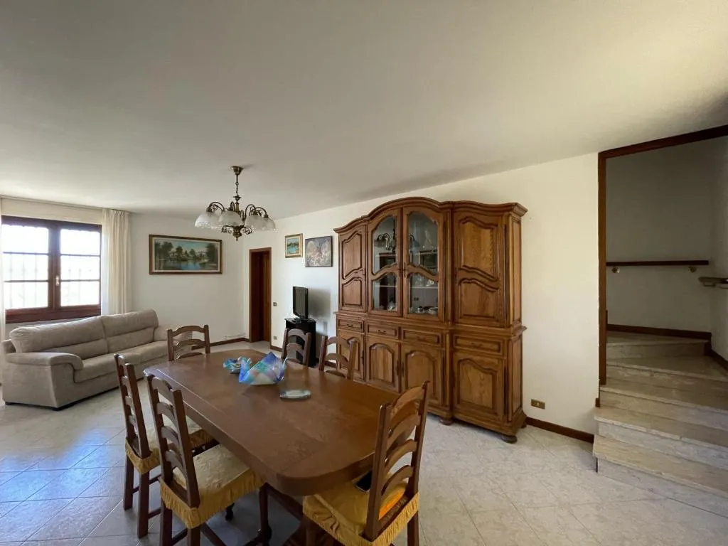 La sala con il divano, il grande tavolo in legno per otto persone e la credenza