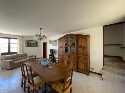 La sala con il divano grigio, il grande tavolo in legno e la credenza